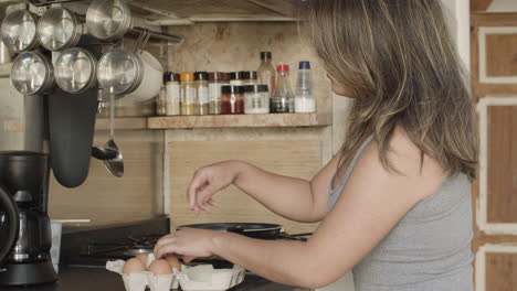 Side-view-of-Japanese-woman-breaking-eggs-for-omelet-in-kitchen