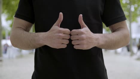 Cropped-shot-of-young-man-showing-thumbs-up-outdoor.