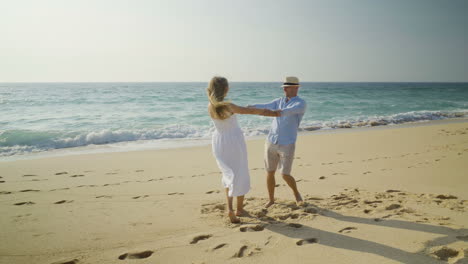Couple-holding-hands-and-turning-around-on-beach