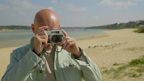 Man-holding-camera-and-photographing-on-beach
