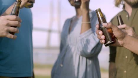 Closeup-shot-of-friends-clinking-beer-bottles-and-dancing