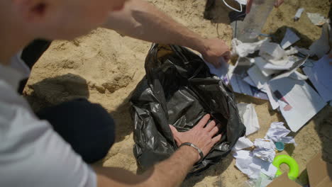 Cropped-shot-of-young-people-picking-garbage-on-beach