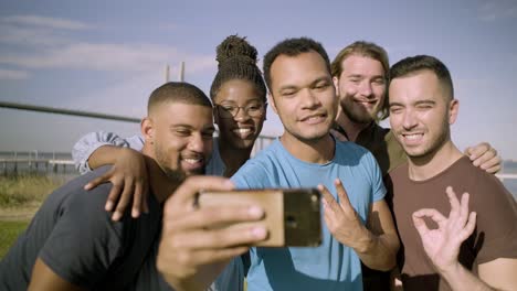 Smiling-friends-gesturing-while-taking-selfie-with-smartphone