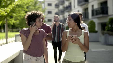 Fröhliche-Junge-Frauen,-Die-Auf-Der-Straße-Reden-Und-Smartphones-Benutzen