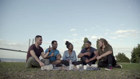 Happy-people-talking-and-drinking-beer-during-picnic