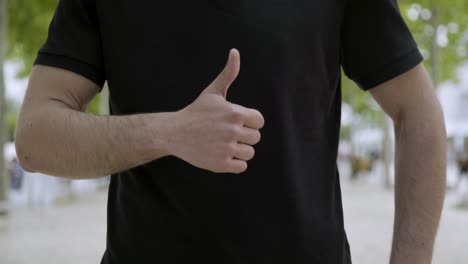 Cropped-shot-of-young-man-showing-thumb-up-outdoor.