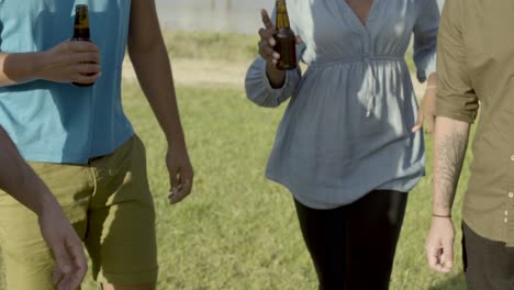 Cropped-shot-of-friends-clinking-beer-bottles-and-dancing