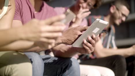Personas-Sentadas-En-Un-Banco-De-Madera-Y-Usando-Dispositivos-Digitales