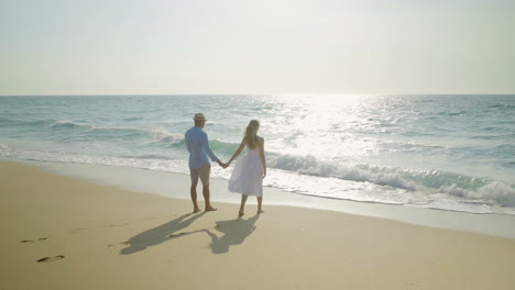 Couple-holding-hands-and-walking-at-seaside