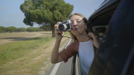 Girl-photographing-with-camera-through-open-car-window