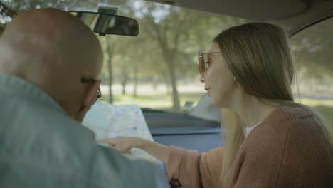 Smiling-couple-looking-at-map-in-car