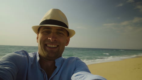 Handsome-man-in-hat-turning-around-on-beach