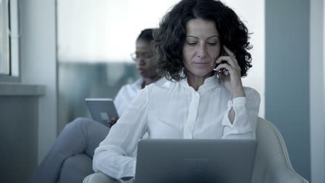 Serious-businesswoman-with-smartphone-and-laptop