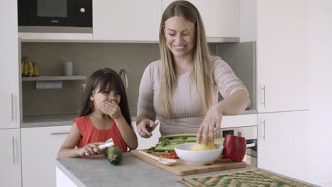 Cheerful-mom-cutting-vegetables-in-kitchen