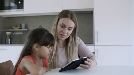 Mom-showing-content-on-tablet-to-little-daughter