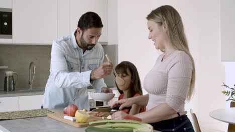 Happy-young-parents-couple-and-little-girl-cooking-dinner