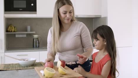 Joyful-mom-cutting-fresh-apples-in-kitchen