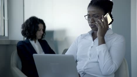 Mujer-De-Negocios-Hablando-Por-Teléfono-Inteligente-Y-Usando-Una-Computadora-Portátil