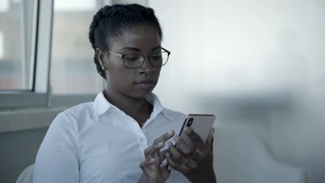 Focused-young-businesswoman-using-smartphone