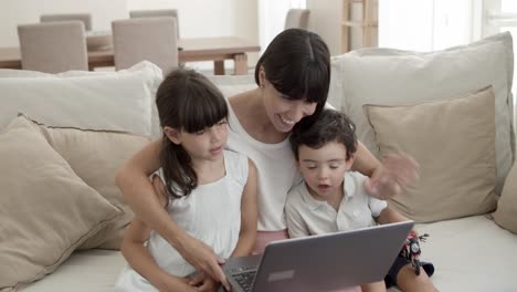 Fröhliche-Mutter-Und-Zwei-Süße-Kinder,-Die-Gemeinsam-Einen-Laptop-Benutzen