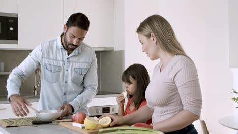 Happy-young-family-couple-and-little-girl-cooking-dinner