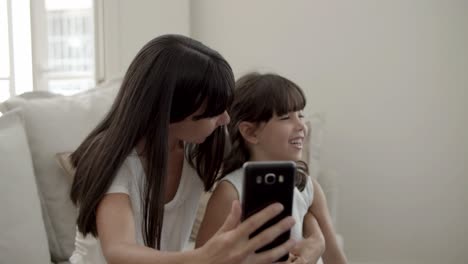 Happy-mom-and-little-daughter-using-smartphone-together