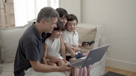 Fröhliche-Eltern-Und-Zwei-Kinder-Mit-Laptop-Im-Wohnzimmer