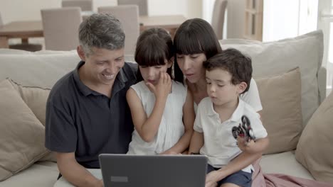 Glückliche-Eltern-Und-Zwei-Kinder-Sitzen-Am-Laptop-Im-Wohnzimmer