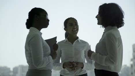 Cheerful-multiethnic-businesswomen-shaking-hands-and-talking