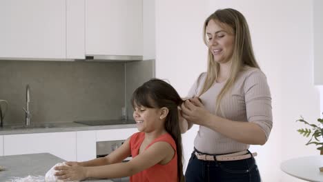 Happy-mom-braiding-daughters-long-hair