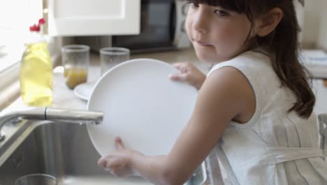 Serious-little-girl-washing-dish-by-herself