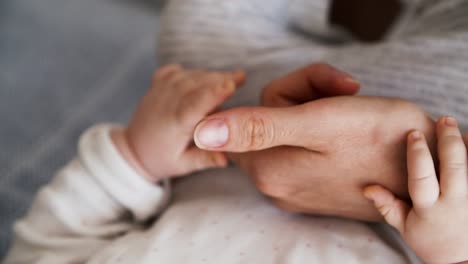 Closeup-of-baby-grabbing-moms-arm-and-finger
