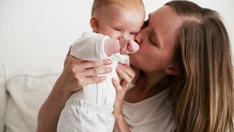 Cheerful-mom-kissing-cute-baby-daughter