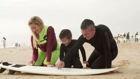 Happy-family-waxing-surfboard-on-beach