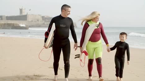 Happy-family-with-surfboard-walking-on-beach