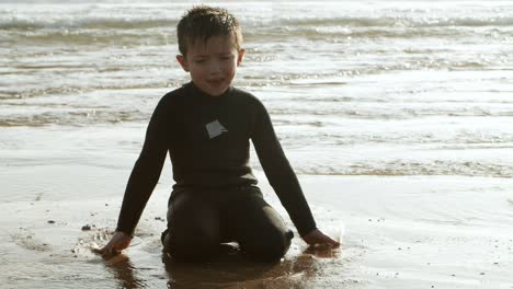 Happy-boy-playing-with-water-on-sea-coast