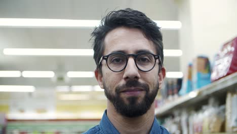 Young-man-smiling-at-camera-in-supermarket