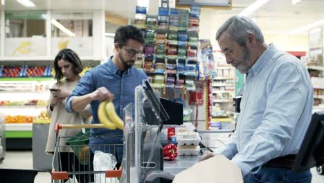 Cashier-and-buyers-at-pay-desk-in-supermarket