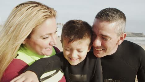 Happy-family-in-wetsuits-smiling-at-camera