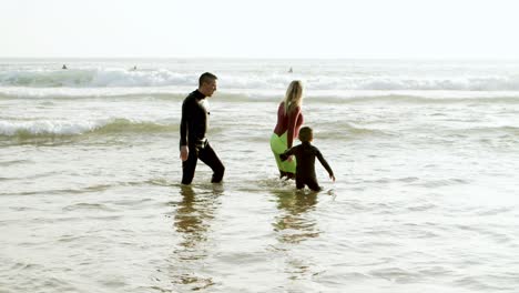 Family-in-wetsuits-walking-in-sea