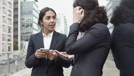 Businesswomen-talking-and-using-smartphones-on-street