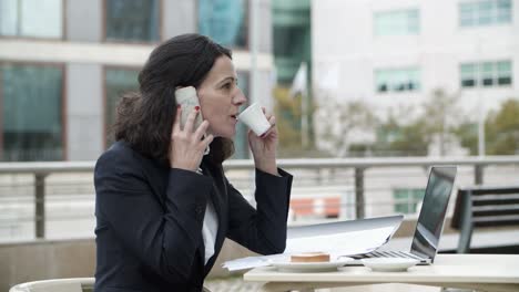 Mujer-De-Negocios-Hablando-Por-Teléfono-Inteligente-Y-Tomando-Café