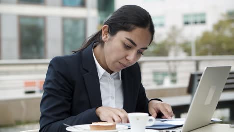 Businesswoman-using-laptop-and-working-with-papers