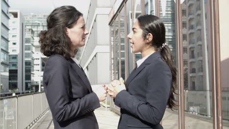 Businesswomen-standing-and-talking-on-street