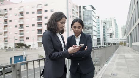 Focused-businesswomen-using-smartphone-on-street