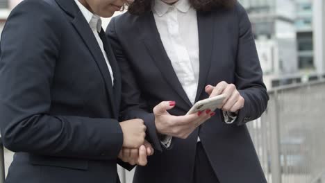 Serious-businesswomen-using-smartphone-on-street