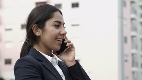 Serious-young-businesswoman-talking-by-smartphone
