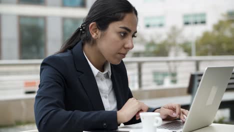 Focused-businesswoman-using-laptop-in-cafe