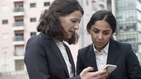 Concentrated-businesswomen-using-smartphone-on-street