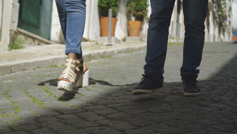 Legs-of-young-people-walking-on-paved-sidewalk.